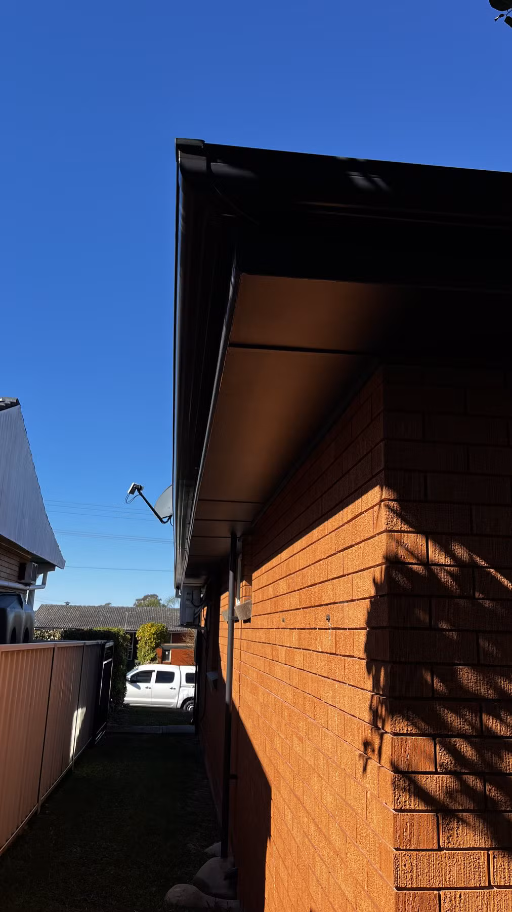 Matt dark eaves beneath a glossy dark gutter and fascia